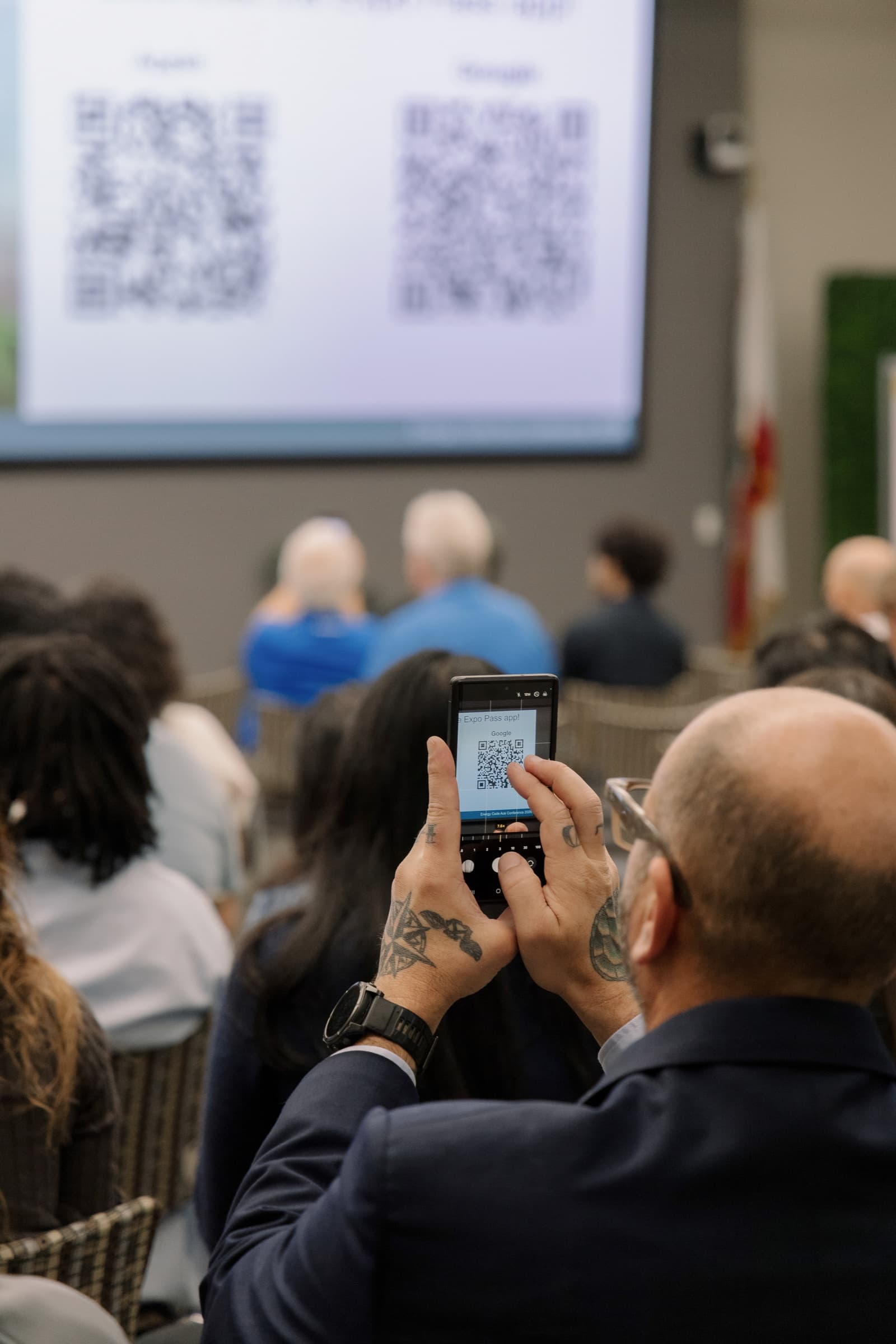 An audience member photographing a QR code on the screen