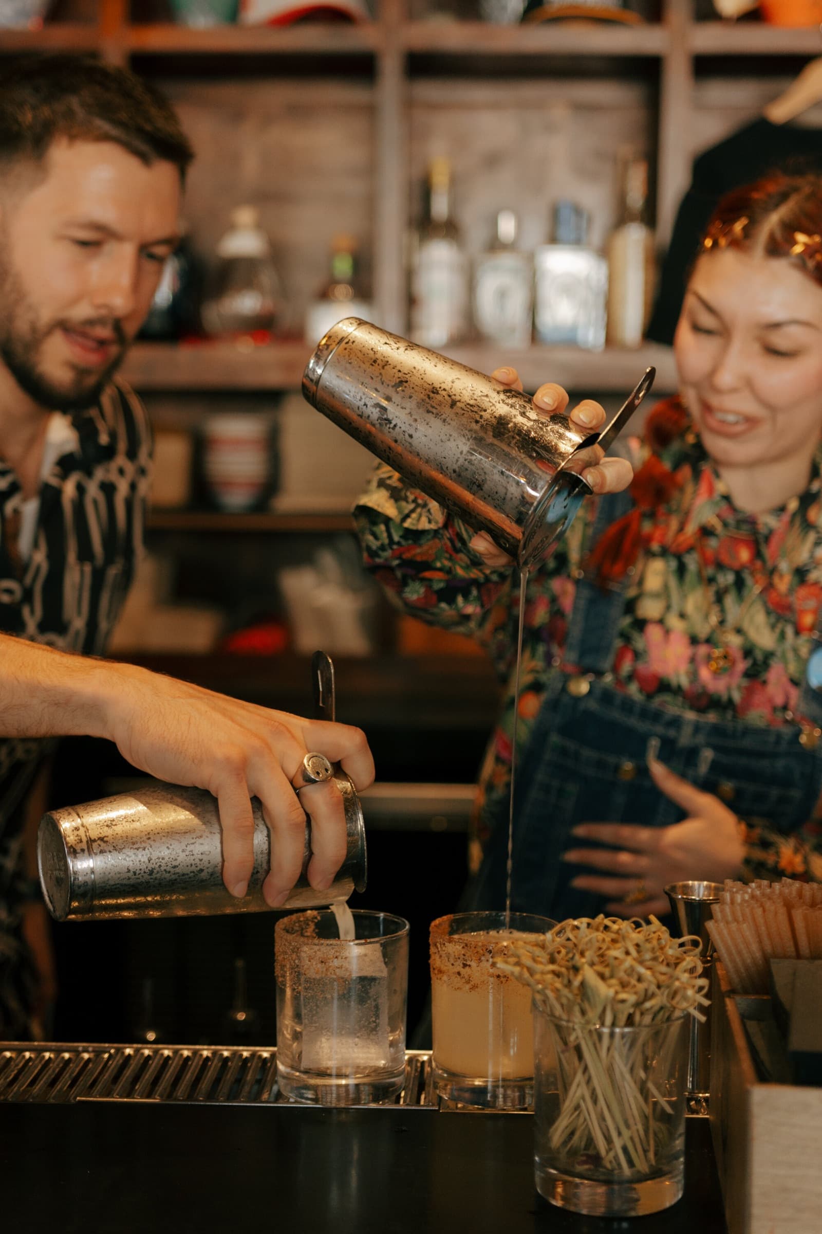 Two bartenders pouring cocktails at the bar