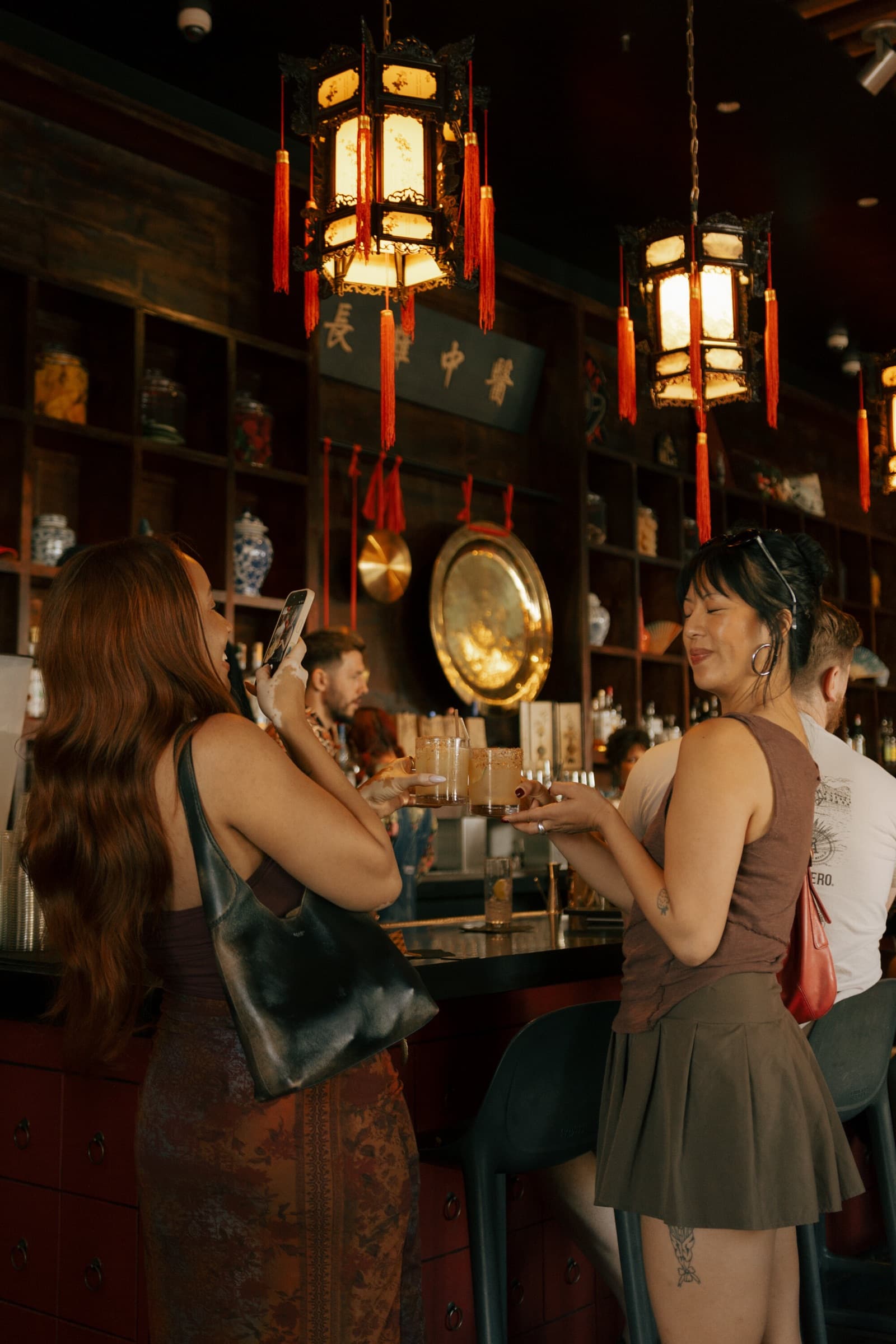 Two women toasting under red lanterns