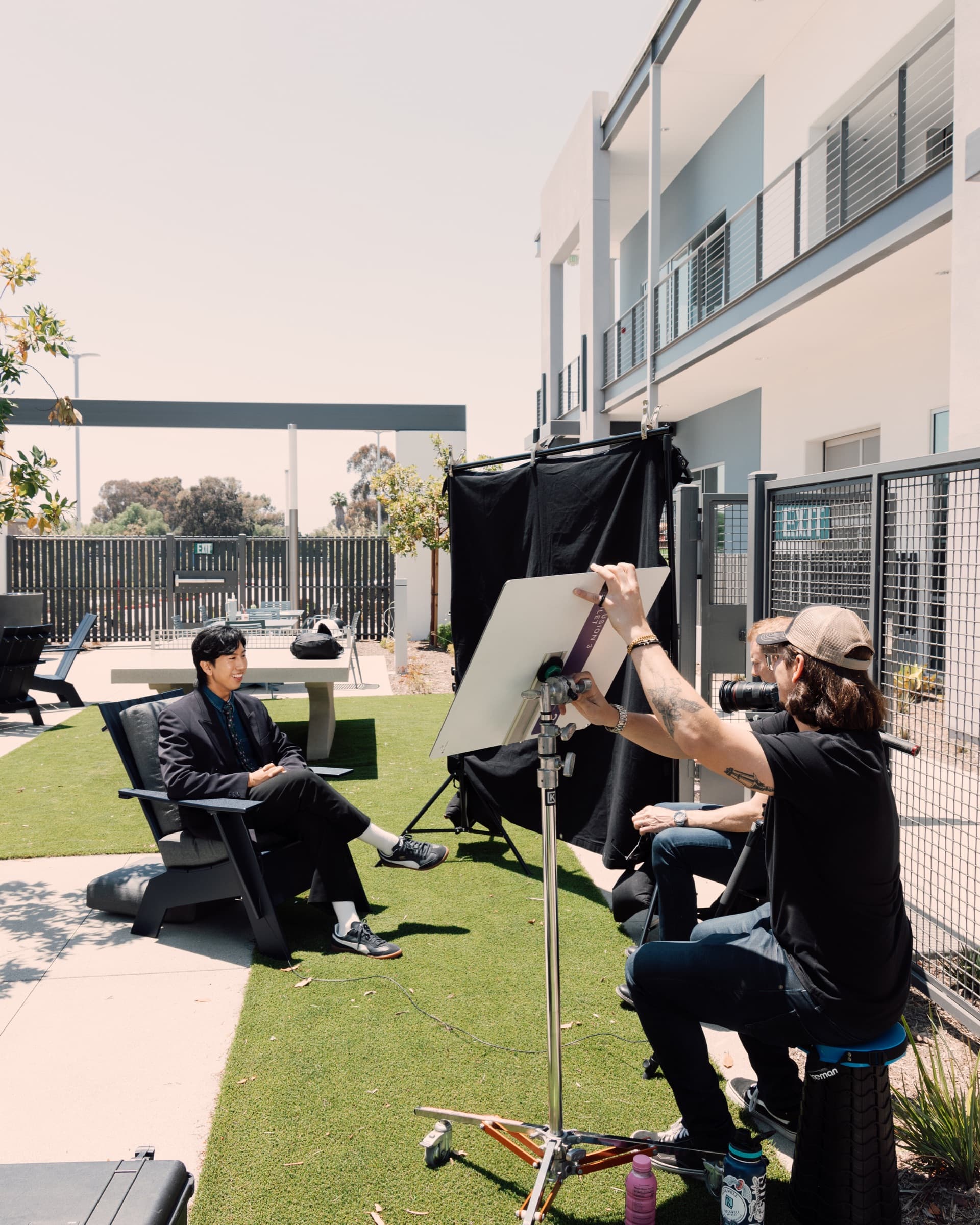 An on-set interview on turf, a crew member holding a bounce card