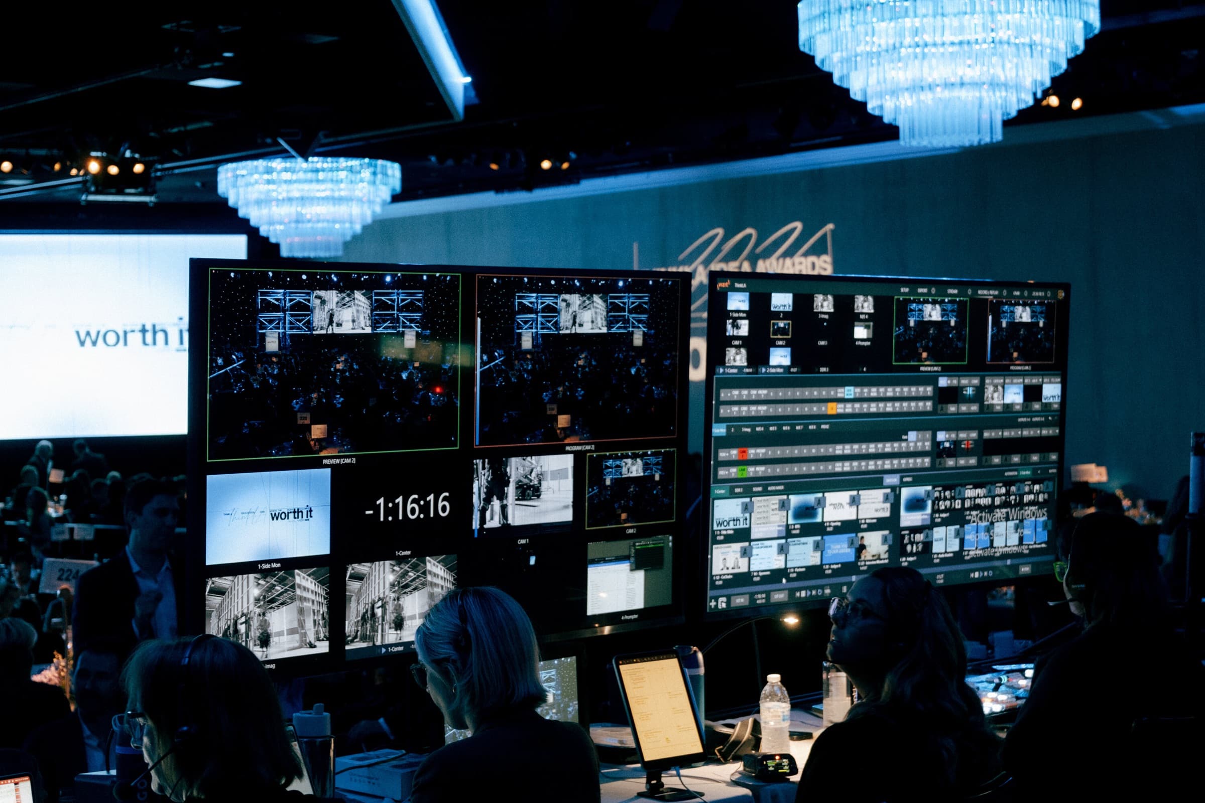 Editors at a video village during an awards show, under blue chandeliers